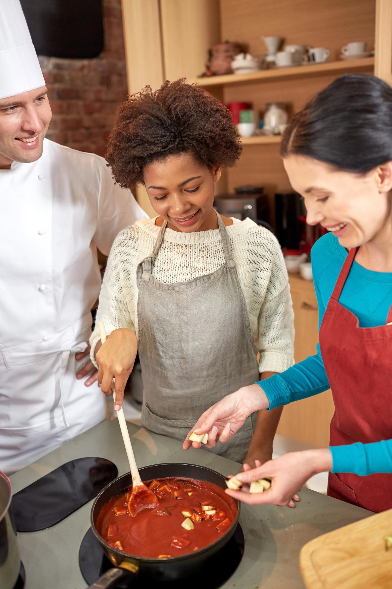 Students stirring pots in bright kitchen